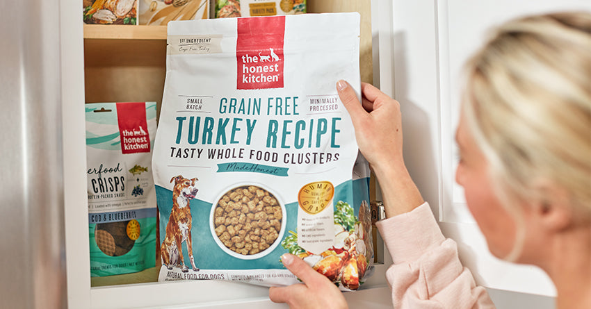 Woman pulling a bag of The Honest Kitchen's Whole Food Clusters out of her cabinet.