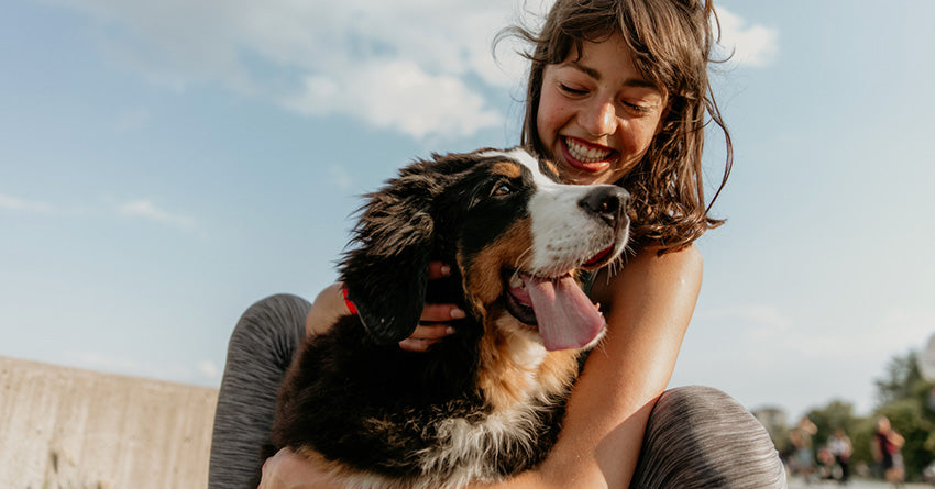 A smiling woman petting a happy, panting dog