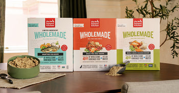The Honest Kitchen's Wholemade Dog Food recipes on a wooden countertop with a bowl of food next to it to illustrate how the product comes to life.