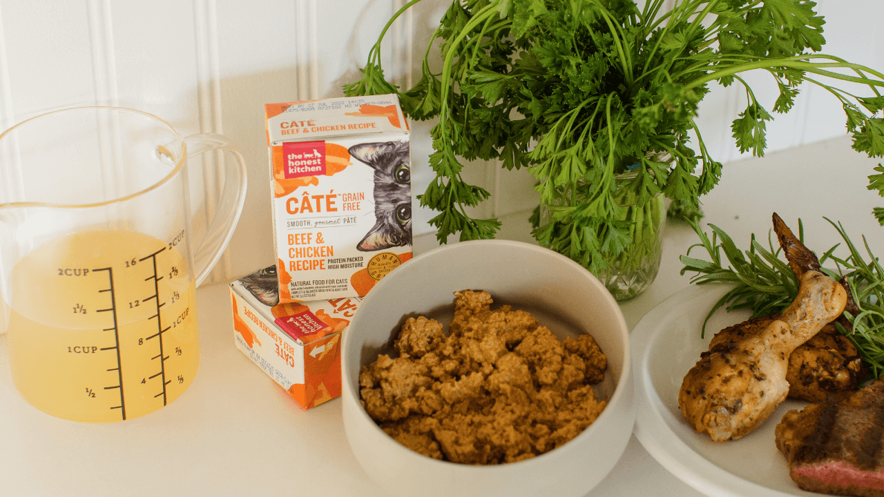 The Honest Kitchen CATE Grain Free Beef & Chicken Recipe cat food is displayed with fresh ingredients. Shop beef cat food from The Honest Kitchen.