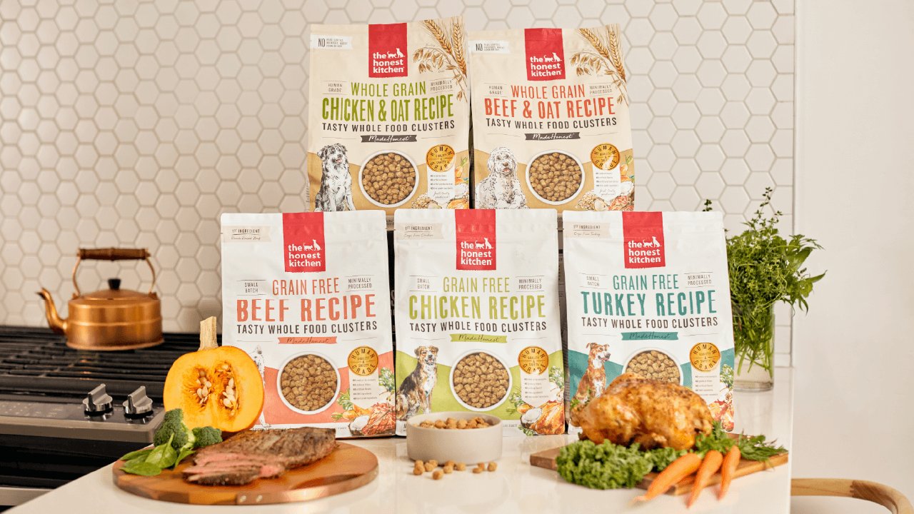 A variety of The Honest Kitchen dog food recipes are displayed with fresh ingredients. Shop healthy, high quality, human grade dry dog food clusters from The Honest Kitchen.