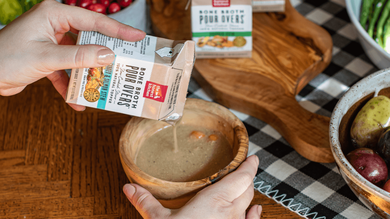 The Honest Kitchen Pumpkin Pour Overs dog food toppers are shown with a bowl of pumpkin puree. Shop healthy Pour Overs dog food toppers from The Honest Kitchen.