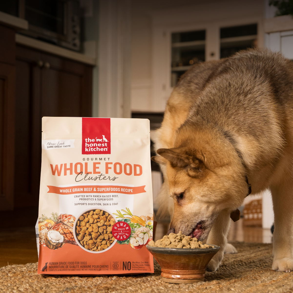 Dog eating from a bowl next to a bag of The Honest Kitchen Whole Food Clusters pet food in a kitchen. Shop human grade dry dog food from The Honest Kitchen.