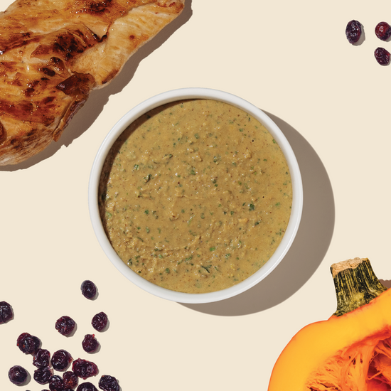bowl of dehydrated cat food from the honest kitchen surrounded by ingredients like cage free chicken, cranberries and pumpkin to illustrate the ingredients included in the recipe.