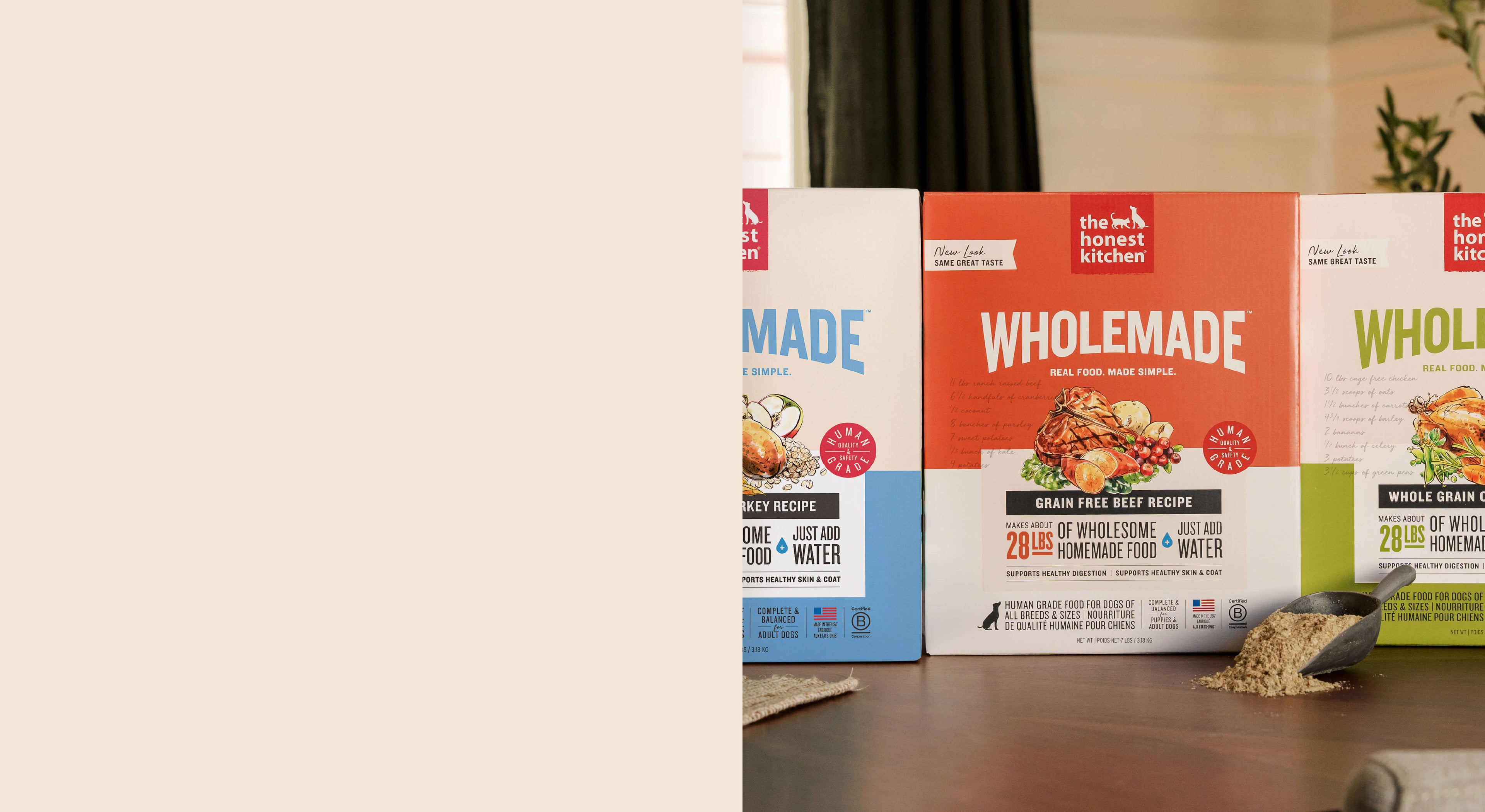 Boxes of The Honest Kitchen Wholemade dehydrated dog food sitting on table with scoop holding food.  Healthy, high quality, human grade food for dogs and cats.